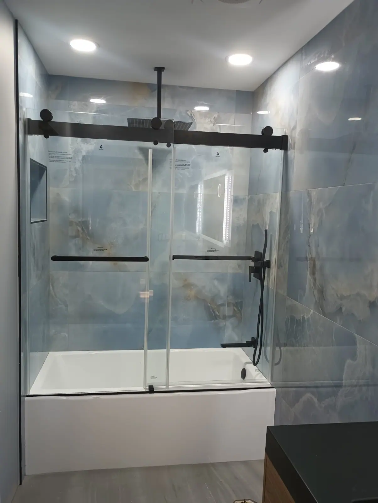 Blue stone tiled bathroom with black sliding glass door