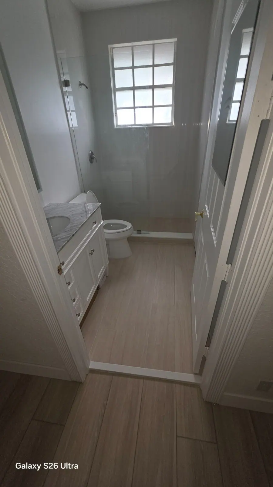 Bright compact bathroom with white vanity and glass shower