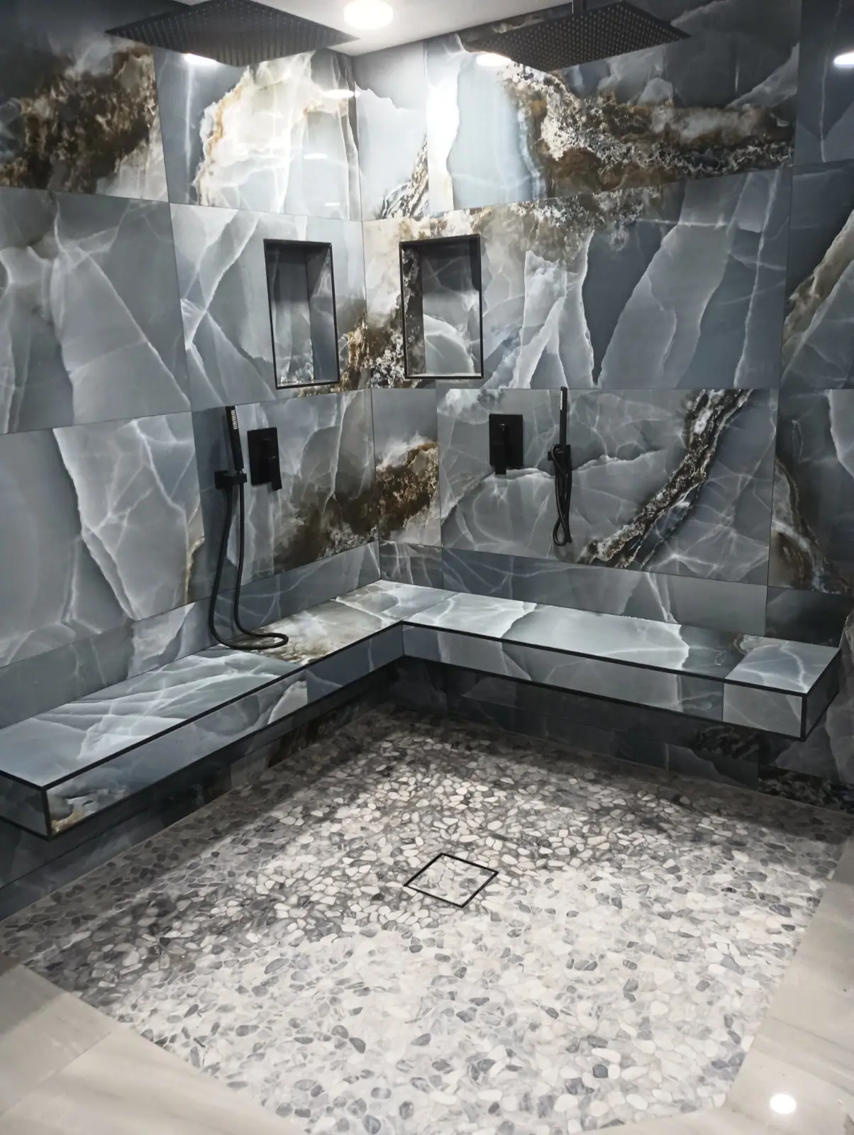 Dramatic dark stone double shower with bench seating