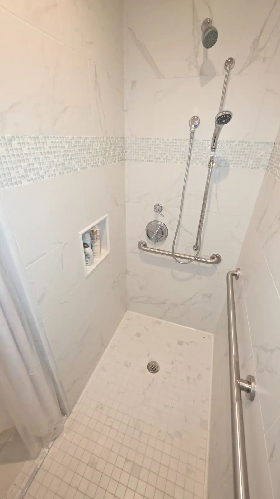 White marble tiled accessible shower with grab bars